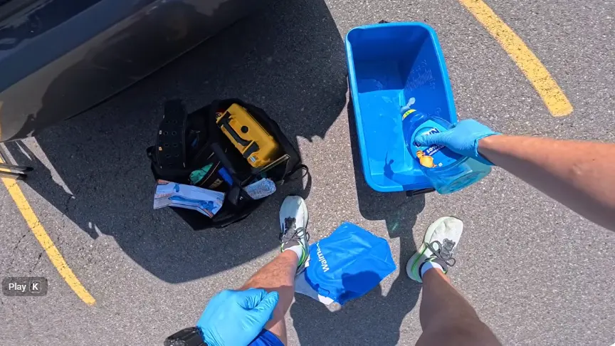 Window cleaning gear set out before a job: bucket, tool bag, spray bottles and blue gloves
