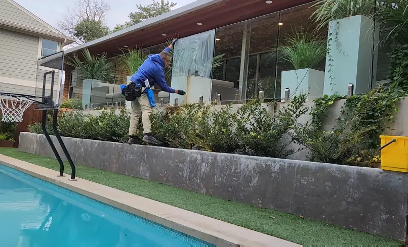 Cleaning Glass Panels Beside a Pool Skylights, Deck Glass and Mirror Cleaning Bellingham: window cleaner using an extension pole on glass panels beside a backyard pool