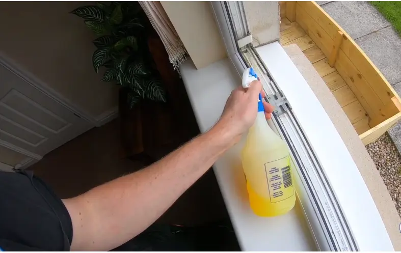 Spraying Cleaner on a Window Track Hand spraying cleaning solution along a window track and sill