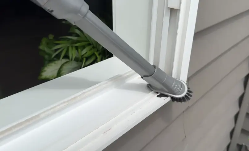 Vacuuming a Window Track Vacuum crevice attachment removing debris from a white window track
